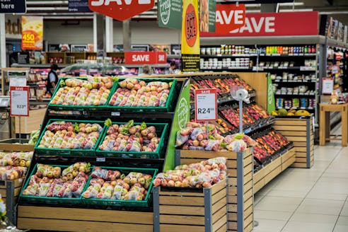 Colorful produce aisle in a supermarket showcasing fresh apples with discount signage.